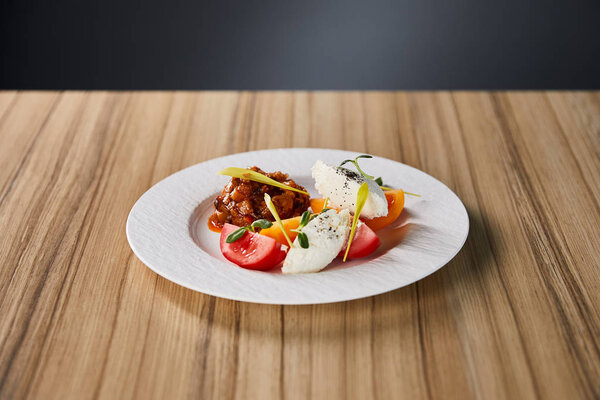 delicious restaurant dish with eggplant caviar and tomatoes on wooden table isolated on grey