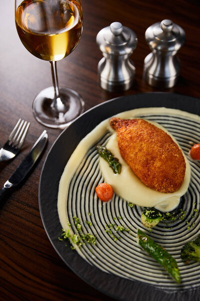 delicious chicken kiev and mashed potato served on plate near cutlery and white wine