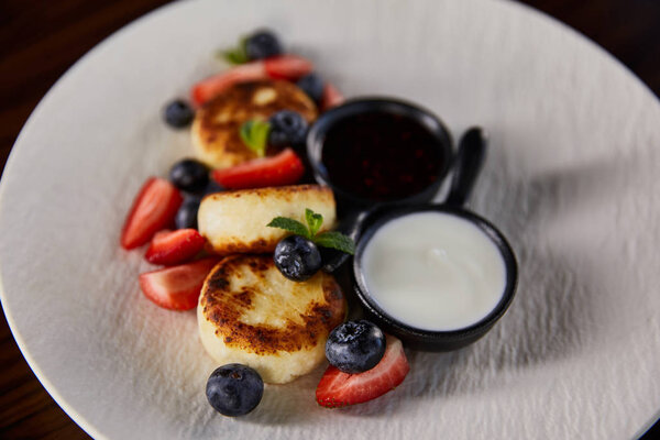 traditional Ukrainian dish syrniki with strawberry, blueberry served with jam and sour cream
