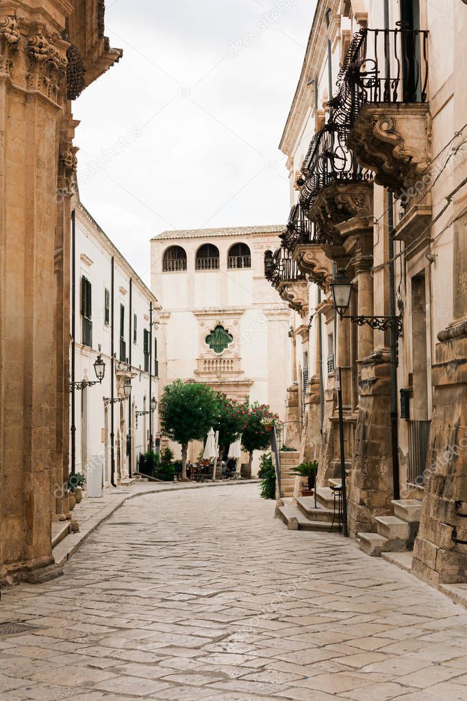 street with paving stones near old buildings with balconies 