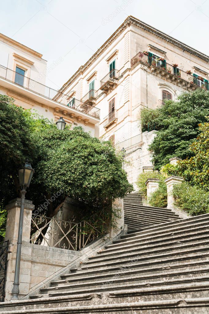 low angle view of plants and trees near stairs and old houses in modica, Italy 