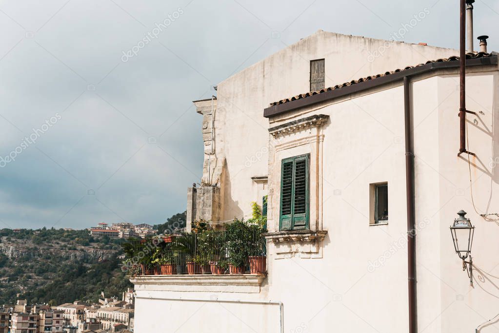 house with plants in flowerpots on balcony in modica, italy 