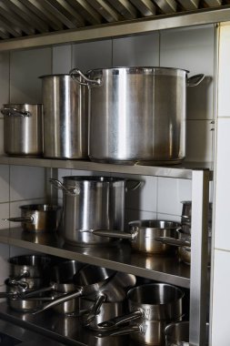 metal pots on rack at kitchen in restaurant clipart
