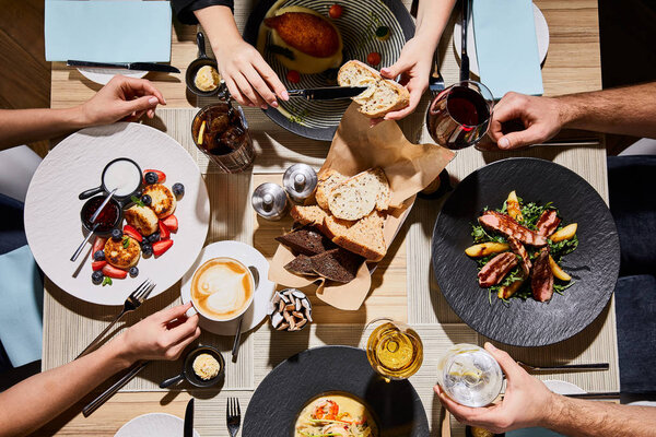 Топ-вид людей, которые едят вкусную еду во время ужина в ресторане
 