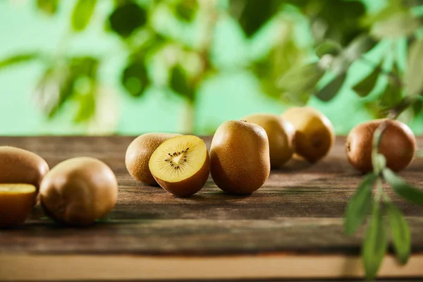 selective focus of cut and whole kiwi on wooden surface 