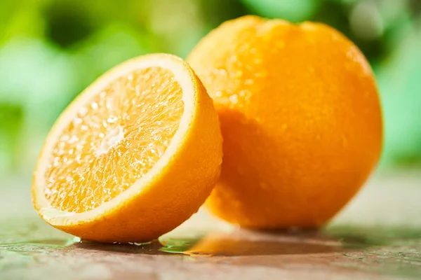 大理石表面滴落的切碎橙子和整个橙子的选择性焦点 — 图库照片