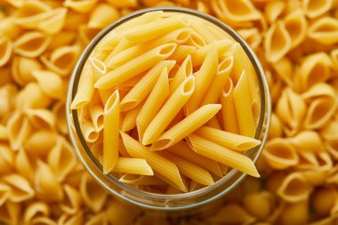 top view of raw penne in jar and around clipart
