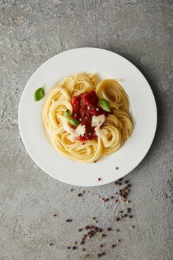 Gri desenli yüzeyde domates soslu leziz spagetti manzarası.