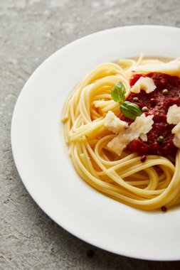 Gri desenli yüzeyde domates soslu lezzetli spagetti.