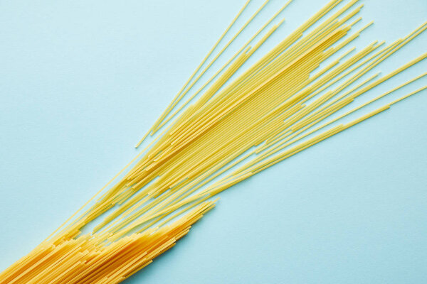 top view of raw spaghetti on blue background with copy space