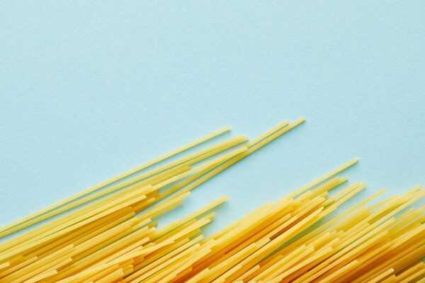 top view of raw spaghetti on blue background with copy space