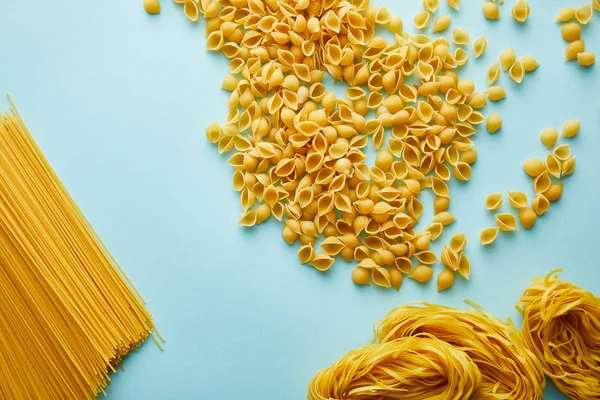 Draufsicht Auf Rohe Conchiglie Linguini Und Spaghetti Auf Blauem Hintergrund — Stockfoto