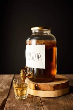 glass jar with kombucha on wooden table isolated on black clipart