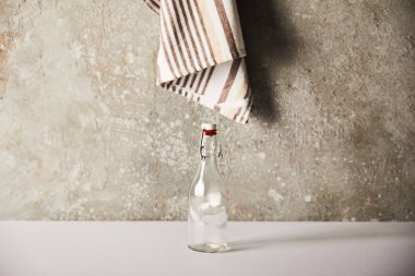 empty glass bottle near striped napkin on stone wall