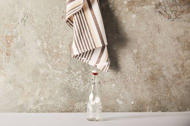 empty glass bottle near striped napkin on stone wall