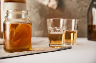 kombucha 'lı kavanozun seçici odak noktası desenli gri arkaplan üzerindeki gözlüklerin yanında