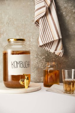 jar with kombucha near glasses on textured grey background with striped napkin clipart