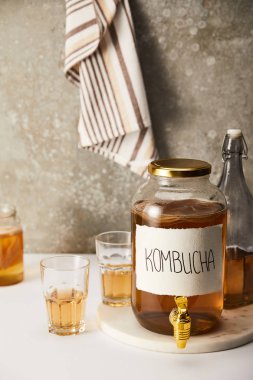 jar with kombucha near glasses on textured grey background with striped napkin clipart