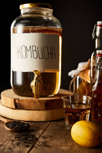 glass jar with kombucha on wooden table isolated on black