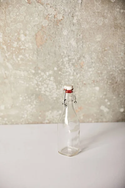 Пустая Стеклянная Бутылка Возле Каменной Серой Стены — стоковое фото