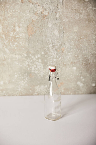empty glass bottle near stone grey wall