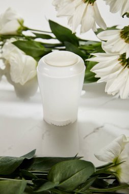 Beyaz yüzeyde çiçekli deodorant şişesi üzerine seçici odaklanma