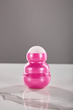 Pembe deodorant şişesinde yuvarlan mermer masada gri renkte izole edilmiş.