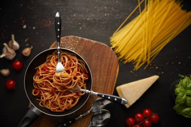 top view of tasty bolognese pasta in frying pan on black background with fresh ingredients clipart