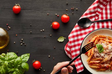 Adamın domates soslu leziz bolonez makarna yiyişini ve siyah ahşap masadaki beyaz tabaktan parmesan peynirini ve peçeteyi kontrol edişini.