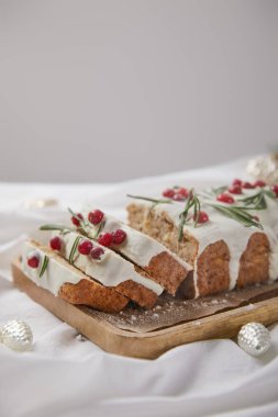 Geleneksel Noel pastası, ahşap tahtada yaban mersinli, gümüş mücevherlerin yanında gri renkte izole edilmiş.