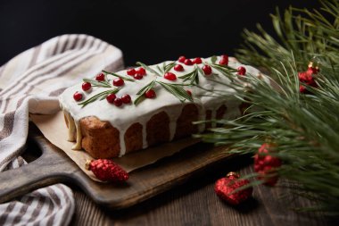 Çam ağacının yanında yabanmersinli geleneksel Noel pastası ve siyah üzerine izole edilmiş ahşap masalarda takılar.