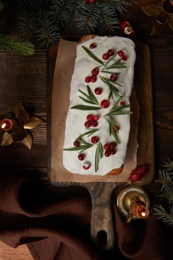 Geleneksel Noel pastası manzarası, çam ağacının yanında kızılcık ve ahşap masa üzerinde mumlar.