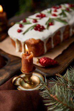 Geleneksel Noel pastasının seçici odağı, ahşap masada yanan bir mum yanında kızılcık.