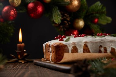 Geleneksel Noel pastasının seçici odak noktası. Noel çelengi yanında. Mücevherlerle süslenmiş.