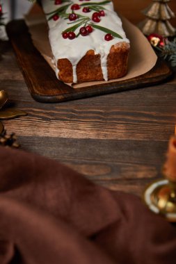 Kahverengi peçeteli, ahşap masada kızılcıklı geleneksel Noel pastası.