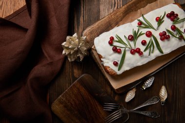 Geleneksel Noel pastanın üst görüntüsü. Mücevherlerin yanında kızılcık, çatal ve kahverengi peçete.