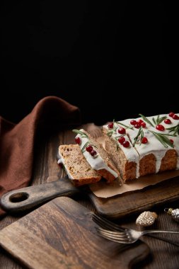 Geleneksel Noel pastası, yaban mersinli, çatallı ve kahverengi peçeteli, ahşap masalı, siyahlı.