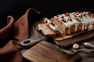 Geleneksel Noel pastası, yaban mersinli, çatallı ve kahverengi peçeteli, ahşap masalı, siyahlı.