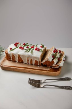 Geleneksel Noel pastası, çatalların yanında yaban mersinli beyaz masada gri üzerine izole edilmiş.