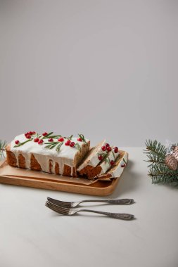 Çatalların, mücevherlerin ve çamların yanında yaban mersinli geleneksel Noel pastası gri masalarda izole edilmiş.