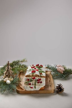 Geleneksel Noel pastası, yaban mersinli. Mücevherlerin yanında ve gri masa üzerinde çam ağacı.