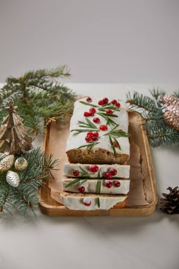 Geleneksel Noel pastası, yaban mersinli. Mücevherlerin yanında ve gri masa üzerinde çam ağacı.