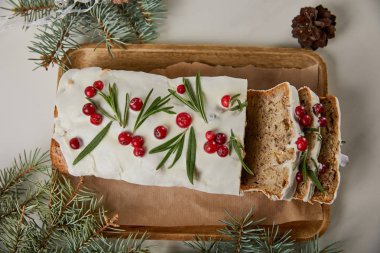 Geleneksel Noel pastası manzarası, çam ağacının yanında kızılcık ve beyaz masa üzerinde koni.