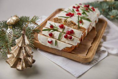 Geleneksel Noel pastasının seçici odak noktası. Mücevherlerin yanında kızılcık ve gri mermer masa üzerinde çam ağacı.