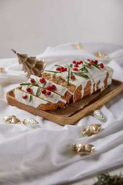 Geleneksel Noel pastası, ahşap tahtada kızılcık, mücevherlerin yanında, gri renkte izole edilmiş beyaz kumaş.