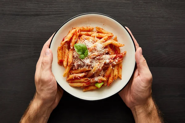 用番茄酱和意大利面在黑色木制背景上端着盘子的人的剪影 — 图库照片