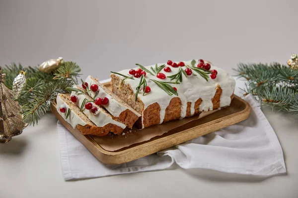 ベイブルズの近くにクランベリーと伝統的なクリスマスケーキグレーに隔離された白いテーブルの上に松 — ストック写真