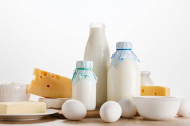 Tahta masadaki taze organik süt ürünleri ve yumurtalar beyaz üzerine izole edilmiş.