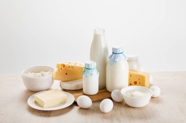 Tahta masadaki taze organik süt ürünleri ve yumurtalar beyaz üzerine izole edilmiş.
