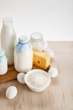 Tahta masadaki taze organik süt ürünleri ve yumurtalar beyaz üzerine izole edilmiş.